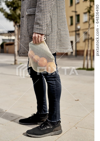 man carrying a mesh bag full of fruit and vegs 64836490
