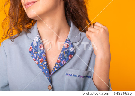 Close up young woman with curly hair in blue home wear. Isolated on yellow background. Close up young woman with curly hair in blue home wear. Isolated on yellow background. 64836650