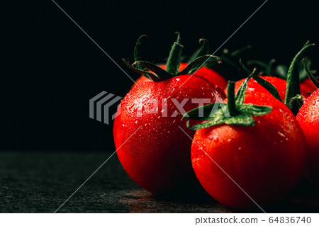 fresh tomatoes with wet and droplet on black stone 64836740