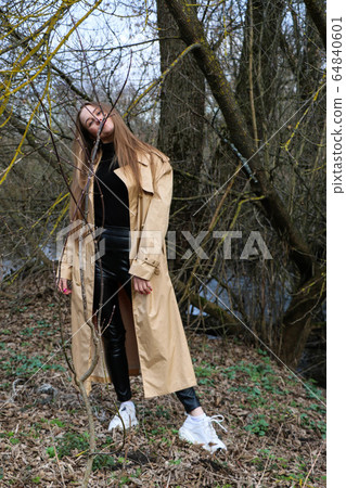beautiful girl, blonde with long hair, walks in the spring near the forest in a brown coat beautiful girl, blonde with long hair, walks in the spring near the forest in a brown coat 64840601