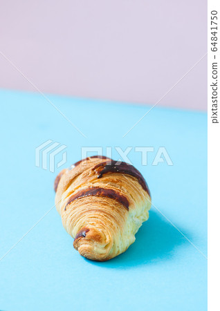 One croissant on a blue background, overhead view. One croissant on a blue background, overhead view. 64841750