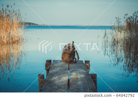 Backpack of traveller on wooden pier. 64842792
