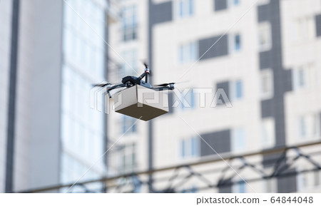 Modern quadrocopter robots delivery methods, blurred city 64844048