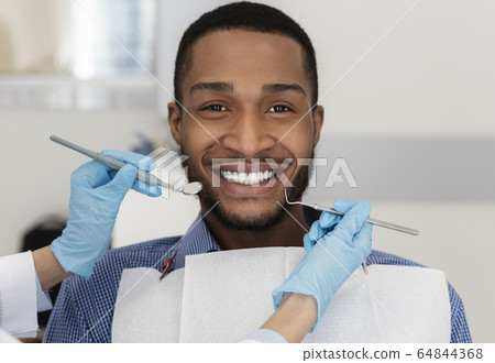 Young black man in dentist chair smiling at camera 64844368