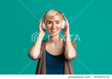 Woman in modern headphones listening to music. Woman in modern headphones listening to music. 64844378