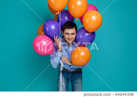 man in shirt holding bright colorful balloons man in shirt holding bright colorful balloons 64844396