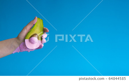 Pink paint dripping from half avocado in hand 64844585
