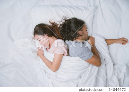 couples woman and man sleeping well in bed hugging soft white pillow. Teenage couples sleep resting couples woman and man sleeping well in bed hugging soft white pillow. Teenage couples sleep resting 64844672
