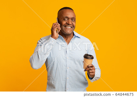 Happy mature african american man with coffee talking on mobile phone Happy mature african american man with coffee talking on mobile phone 64844675