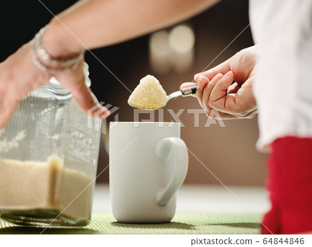 Woman Adding Lots Of Sugar With Teaspoon To Coffee Mug 64844846