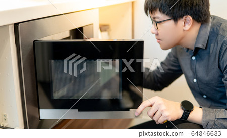 Asian man opening microwave door 64846683