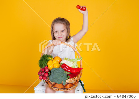Beautiful little girl holding a basket of ripe vegetables Beautiful little girl holding a basket of ripe vegetables 64847000