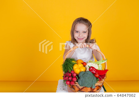 Beautiful little girl holding a basket of ripe vegetables Beautiful little girl holding a basket of ripe vegetables 64847002