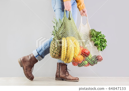 Unrecognizable girl caries two mesh shoppers with 64847133