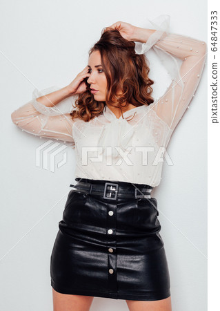 portrait of a beautiful woman with curls in a blouse and a black skirt portrait of a beautiful woman with curls in a blouse and a black skirt 64847333