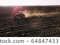 Farm tractor raising dust with harrow plow preparing land for sowing. Agriculture industry, cultivation of land. 64847433