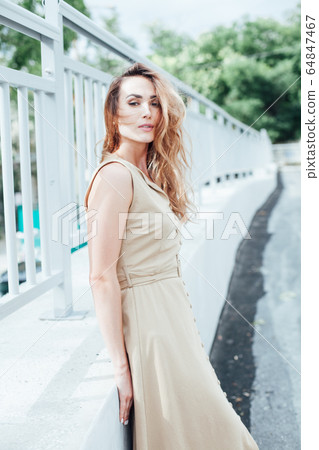 Portrait of a beautiful fashionable blonde woman in a beige dress 64847467