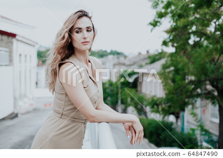 Portrait of a beautiful fashionable blonde woman in a beige dress 64847490