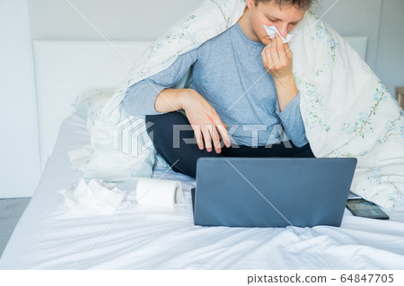 Young caucasian sick man blowing his nose sitting Young caucasian sick man blowing his nose sitting 64847705