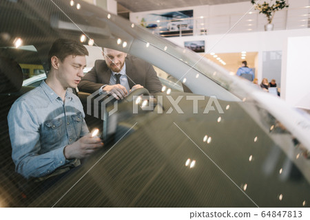 Handsome young man testing of new car in auto dealership 64847813