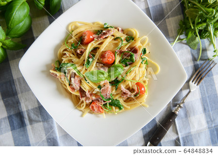 Spaghetti pasta with rucola, cherry tomatoes and Spaghetti pasta with rucola, cherry tomatoes and 64848834