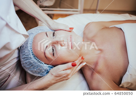Cosmetology doctor makes woman treatments facial massage 64850050