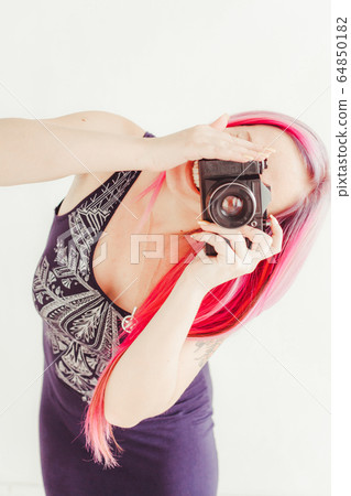 photographer girl with pink hair on a photo shoot with a camera 64850182