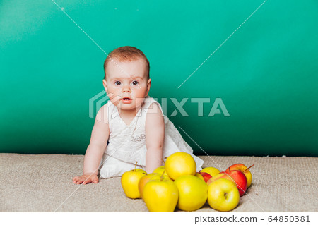 baby girl in a dress with Green apples 64850381