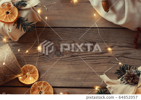 Zero waste christmas concept. Packed in natural fabric gifts and decorations from natural materials with christmas lights on wooden table, top view Zero waste christmas concept. Packed in natural fabric gifts and decorations from natural materials with christmas lights on wooden table, top view 64852057
