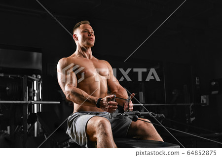 Fit and muscular man trains chest muscles on a block simulator in a gym. An ideal fitness model, trained in the gym. Sport banner, copy space, fitness motivation. Fit and muscular man trains chest muscles on a block simulator in a gym. An ideal fitness model, trained in the gym. Sport banner, copy space, fitness motivation. 64852875