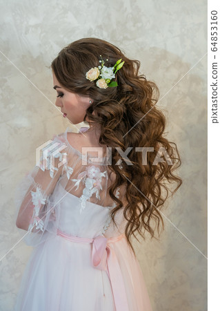 A girl with spinners demonstrates a wedding hairstyle. 64853160