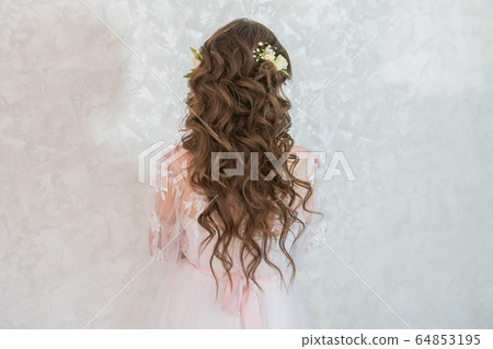 A girl with spinners demonstrates a wedding hairstyle. A girl with spinners demonstrates a wedding hairstyle. 64853195