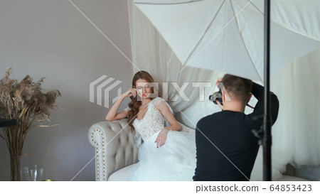 Girl model in a white dress posing in front of the photographer. 64853423