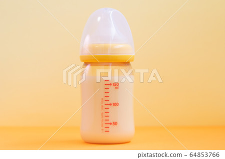 Baby bottle and toys with yellow background 64853766