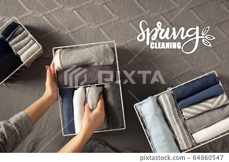 Spring cleaning of closet. Vertical tidying up storage. Neatly folded clothes in the metal white baskets for wardrobe. Grey background. 64860547