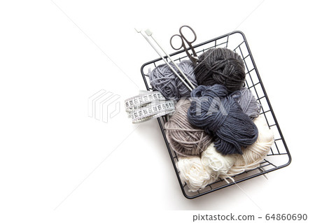 Yarn of gray, white and dark shades in a black metal basket. Knitting needles. Nordic style. Minimalism. 64860690