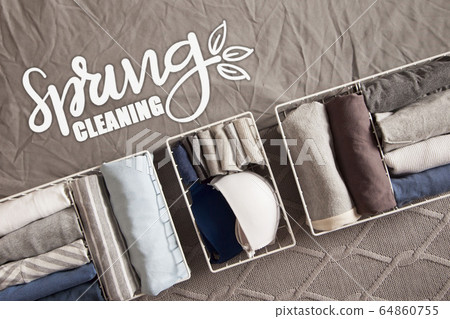 Spring cleaning of closet. Vertical tidying up storage. Neatly folded clothes in the metal white baskets for wardrobe. Grey background. 64860755