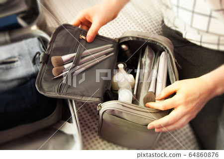 Open grey suitcase with different clothes and cosmetics packed for journey at home. Nordic style minimalism. woman packing bags for holidays and preparing things for vacations getting ready for travel 64860876