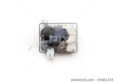 Yarn of gray, white and dark shades in a black metal basket. Knitting needles. Nordic style. Minimalism. Yarn of gray, white and dark shades in a black metal basket. Knitting needles. Nordic style. Minimalism. 64861193