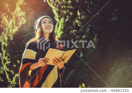 Asian woman relax in the holiday. Travel nature and  write a note in the notebook at the park 64861583
