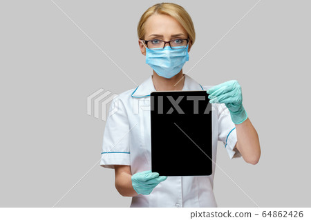 medical doctor nurse woman wearing protective mask and gloves - holding tablet pc 64862426