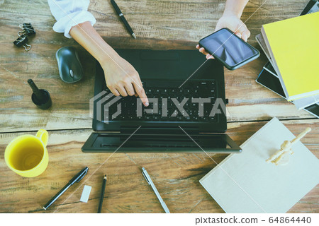 woman young working with a smartphone while working with a laptop 64864440