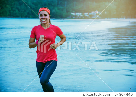 Woman jogging workout on the beach in the morning. Relax with the sea walk. Woman jogging workout on the beach in the morning. Relax with the sea walk. 64864449