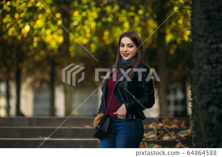 Stylish beautiful lady in a black leather jacket with a black bag and burgundy blouse Stylish beautiful lady in a black leather jacket with a black bag and burgundy blouse 64864588