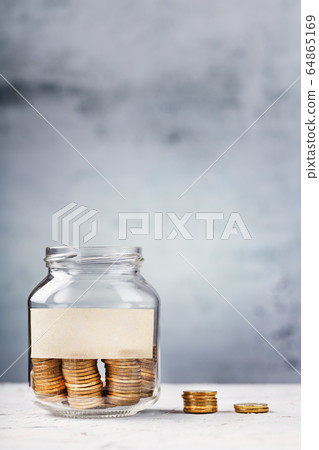 Glass Jar with gold coins and text sticker on a Glass Jar with gold coins and text sticker on a 64865169