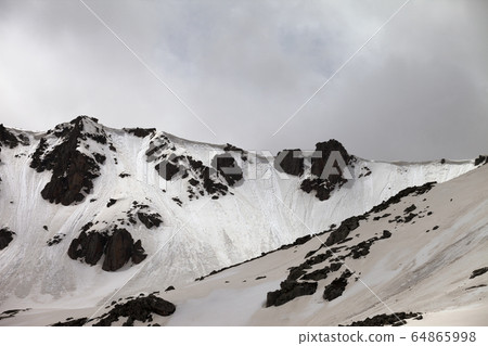 Rocks with snow cornice and traces from avalanche Rocks with snow cornice and traces from avalanche 64865998