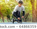 young man runner tying shoelace in park ready for running in morning . sport outdoors healthy 64866359