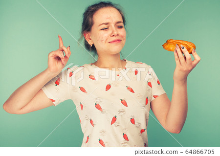 Portrait of pimply teen girl wants to eat eclair Portrait of pimply teen girl wants to eat eclair 64866705