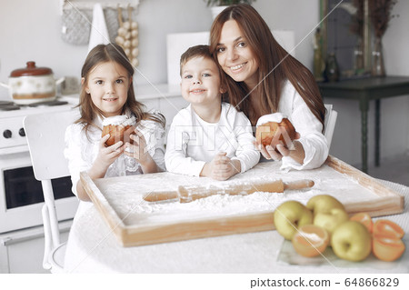 Family sitting in a kitchen and cook the dough for cake Family sitting in a kitchen and cook the dough for cake 64866829