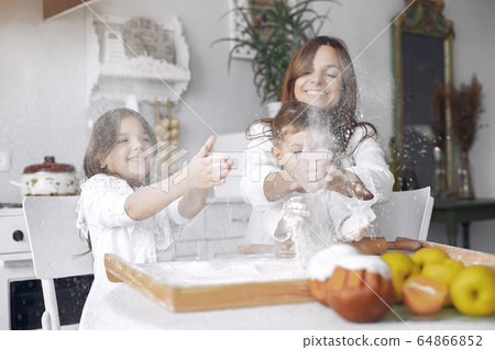 Family sitting in a kitchen and cook the dough for cake Family sitting in a kitchen and cook the dough for cake 64866852